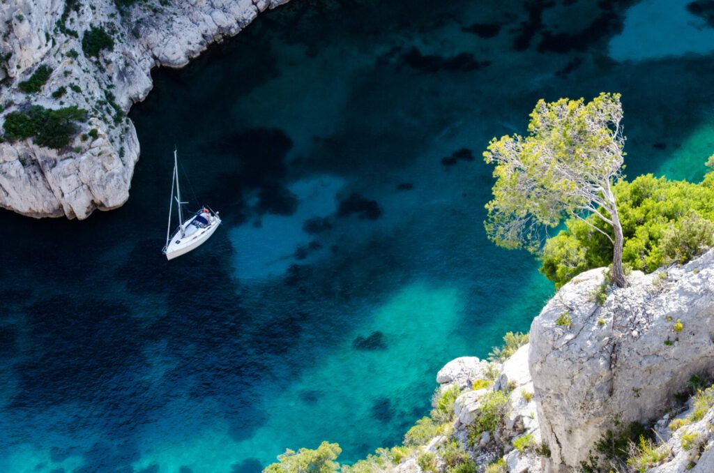 Baum überhängt ein Segelboot in der Calanque En-Vau in der Nähe von Cassis und Marseille.