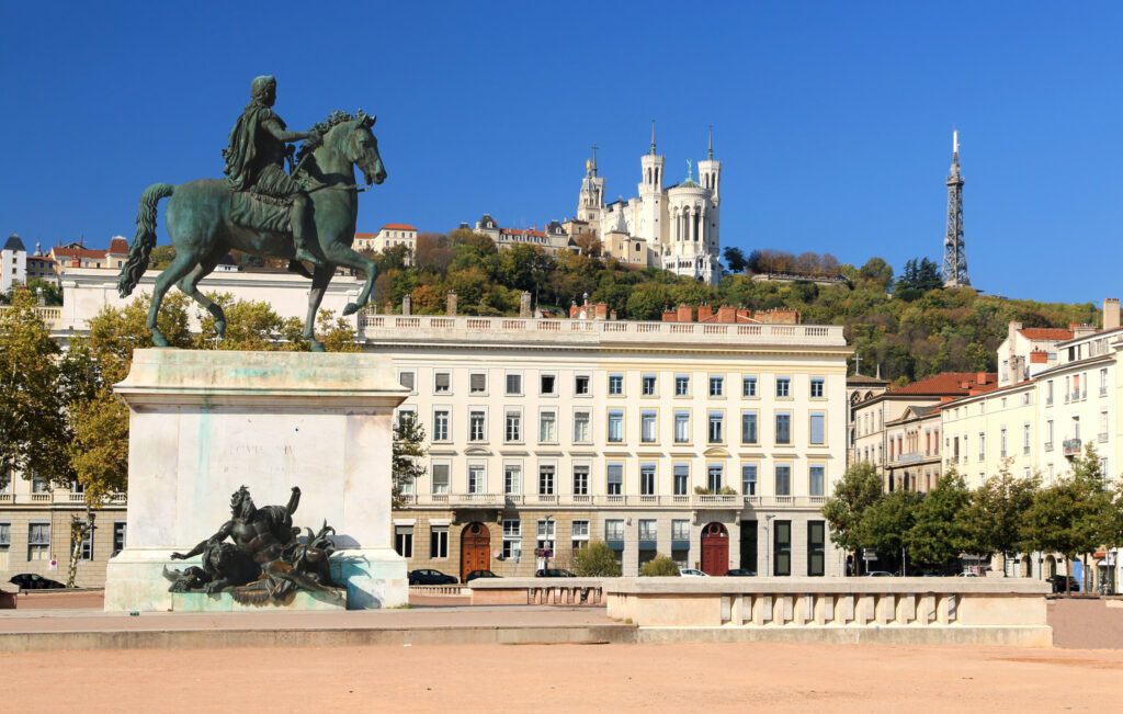 Die Statue von Ludwig IX. auf dem Place Bellecour in Lyon mit der Basilika von Fourvière im Hintergrund.
