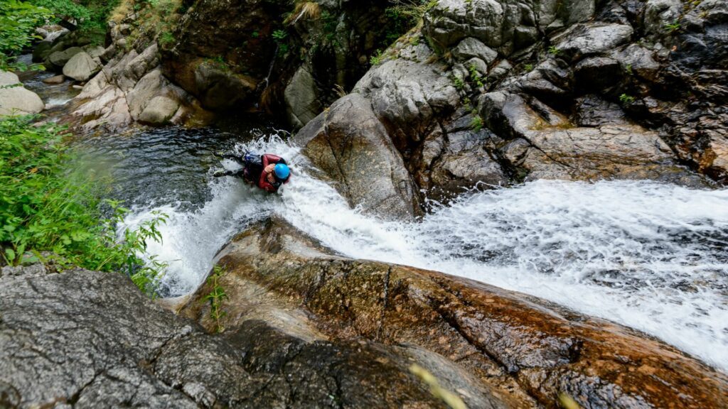 High Angle shot of people canyoning through a stream on the side of a mountain in France